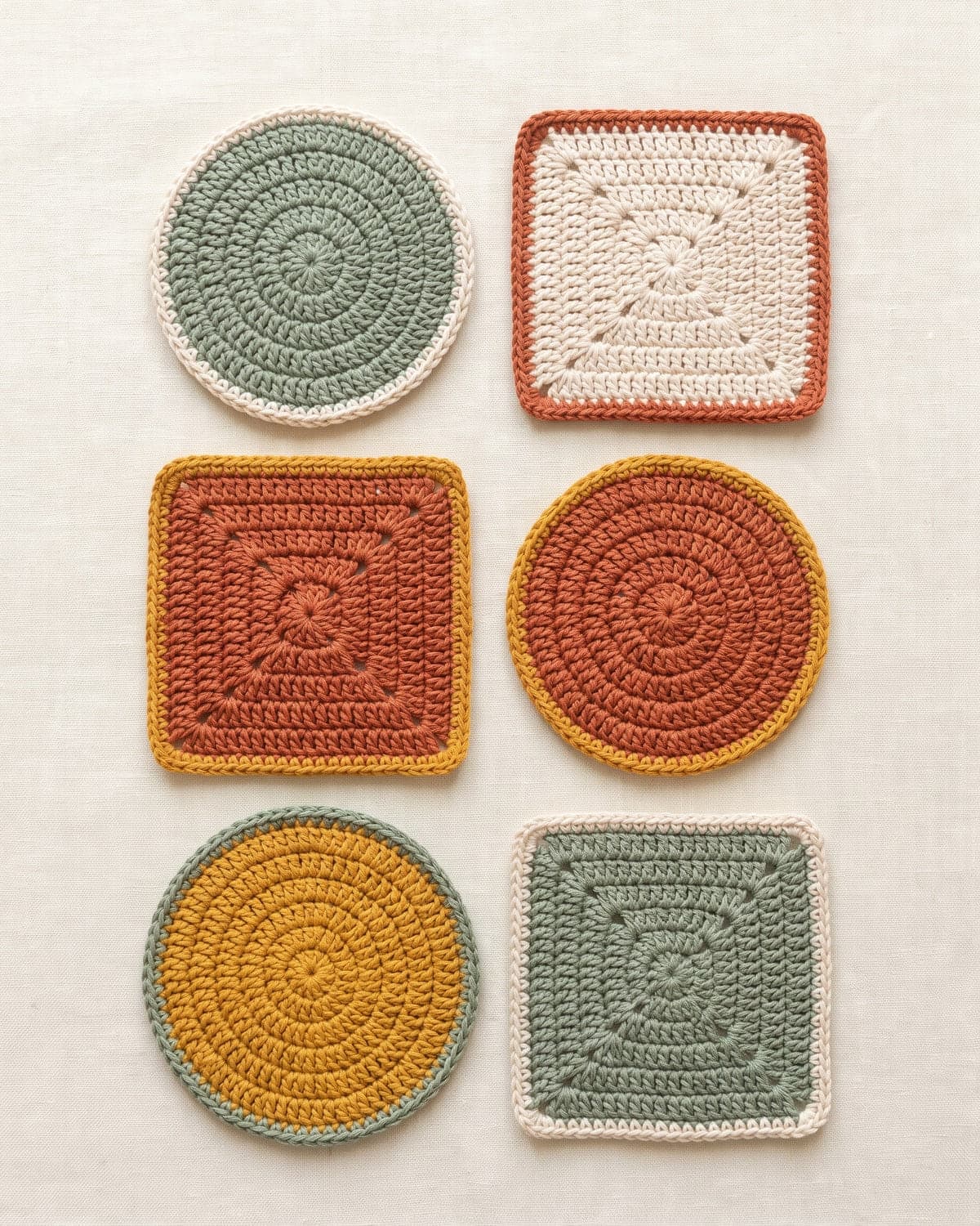 Six round and square crochet coasters in sage, terracotta, mustard and cream with contrast borders