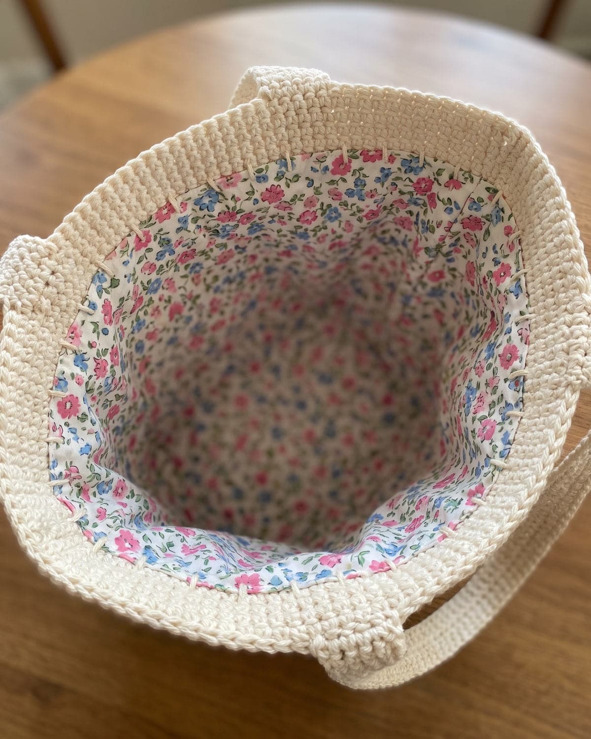 Looking into a cream crochet tote bag lined with floral cotton fabric