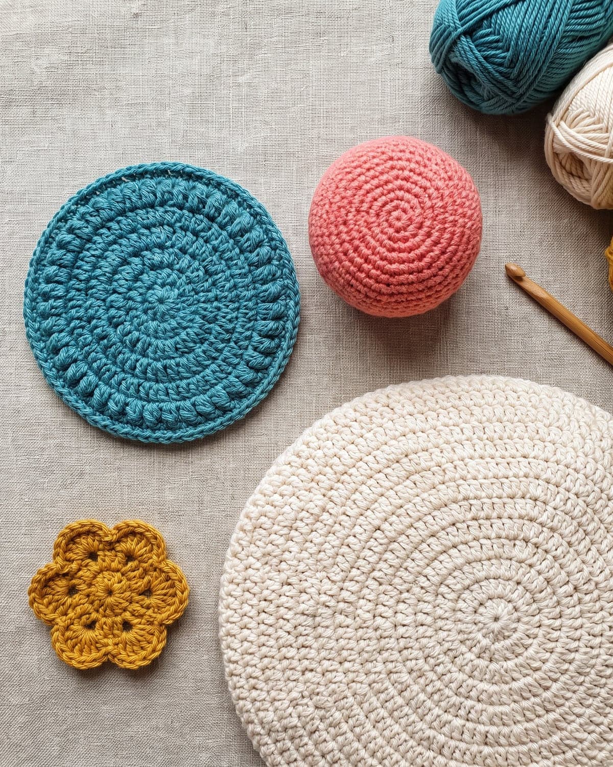 Teal crochet coaster, coral amigurumi ball, cream hat crown and a mustard flower, all started from a closed centre