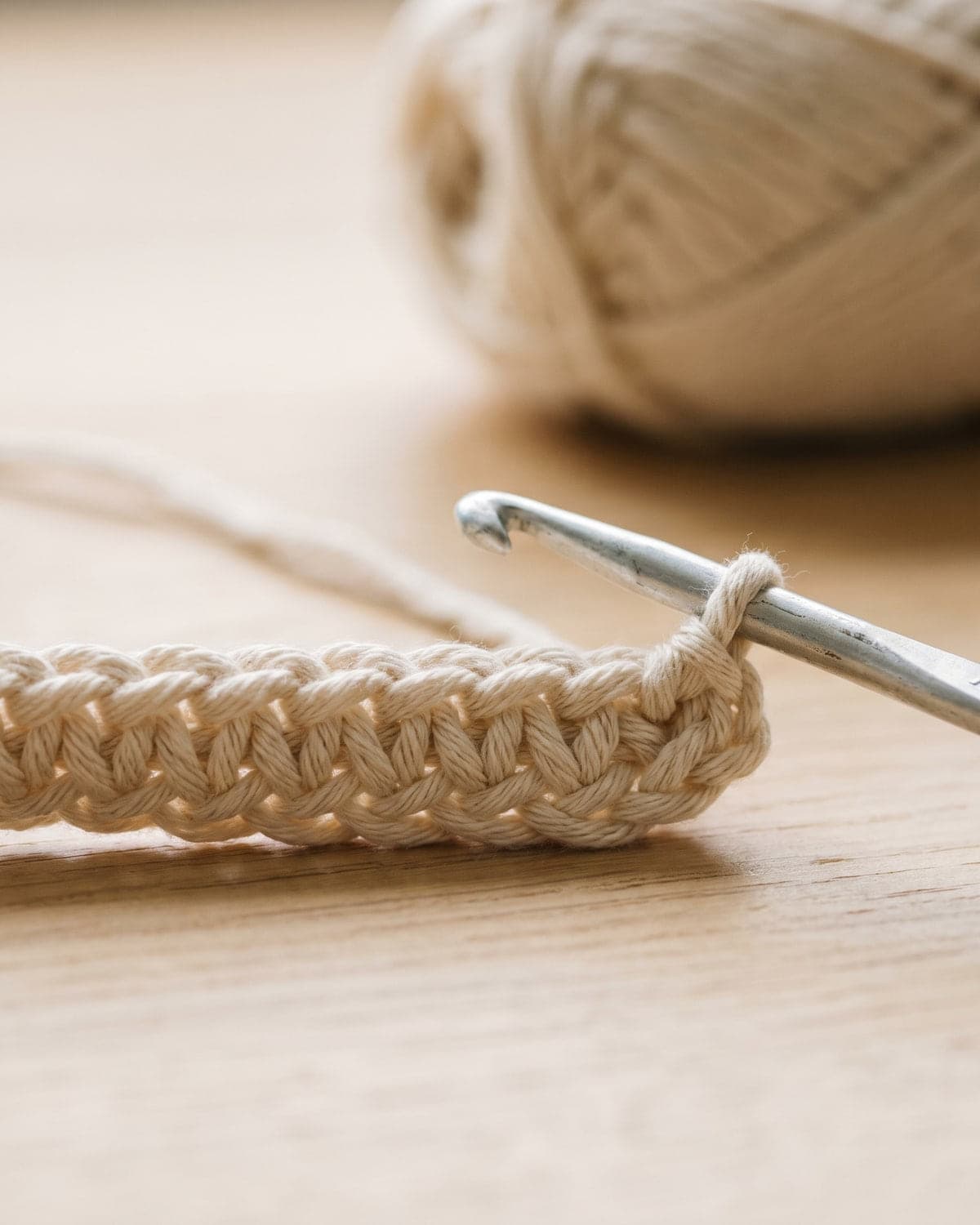 Close-up of a cream crochet foundation chain with the last loop on an aluminium hook