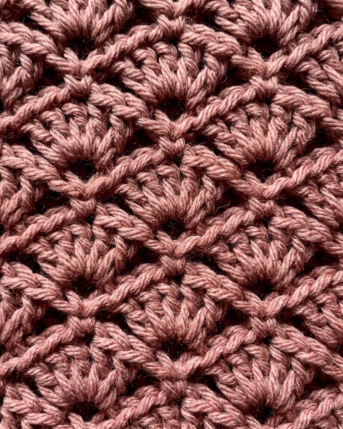 Close-up of staggered rows of crochet shell stitch fans in dusty rose yarn