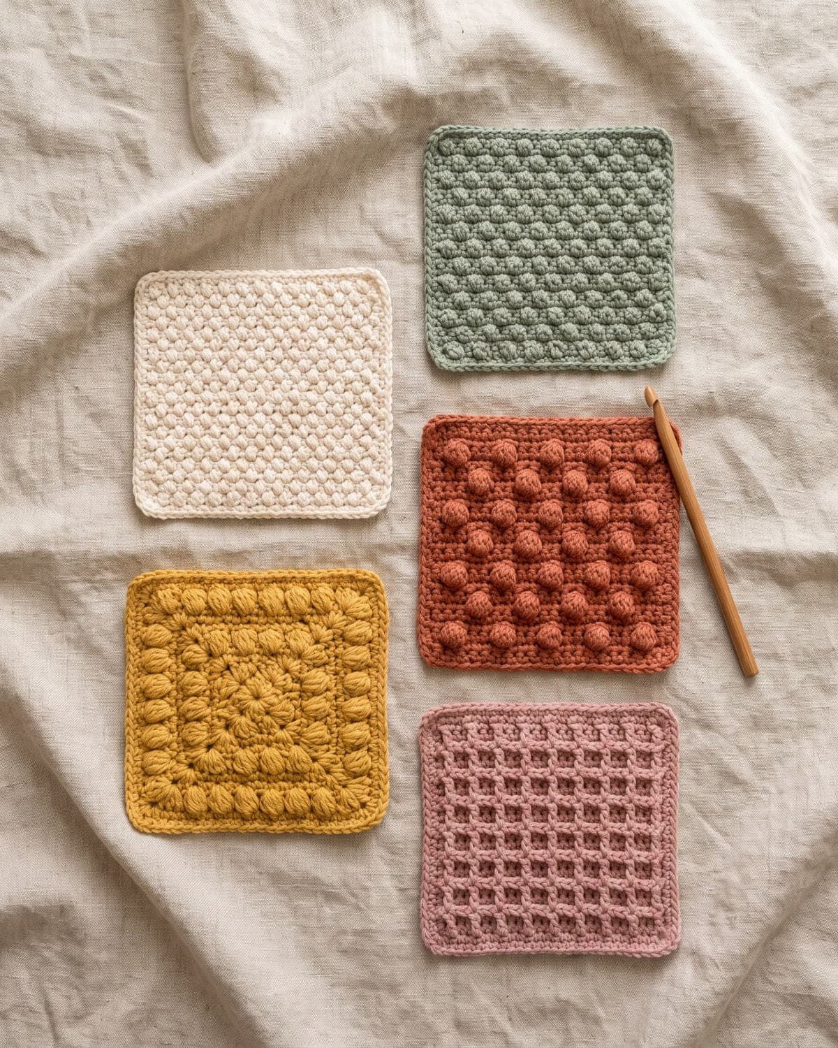 Five square crochet swatches with different raised textures in cream, sage, terracotta, mustard and dusty pink