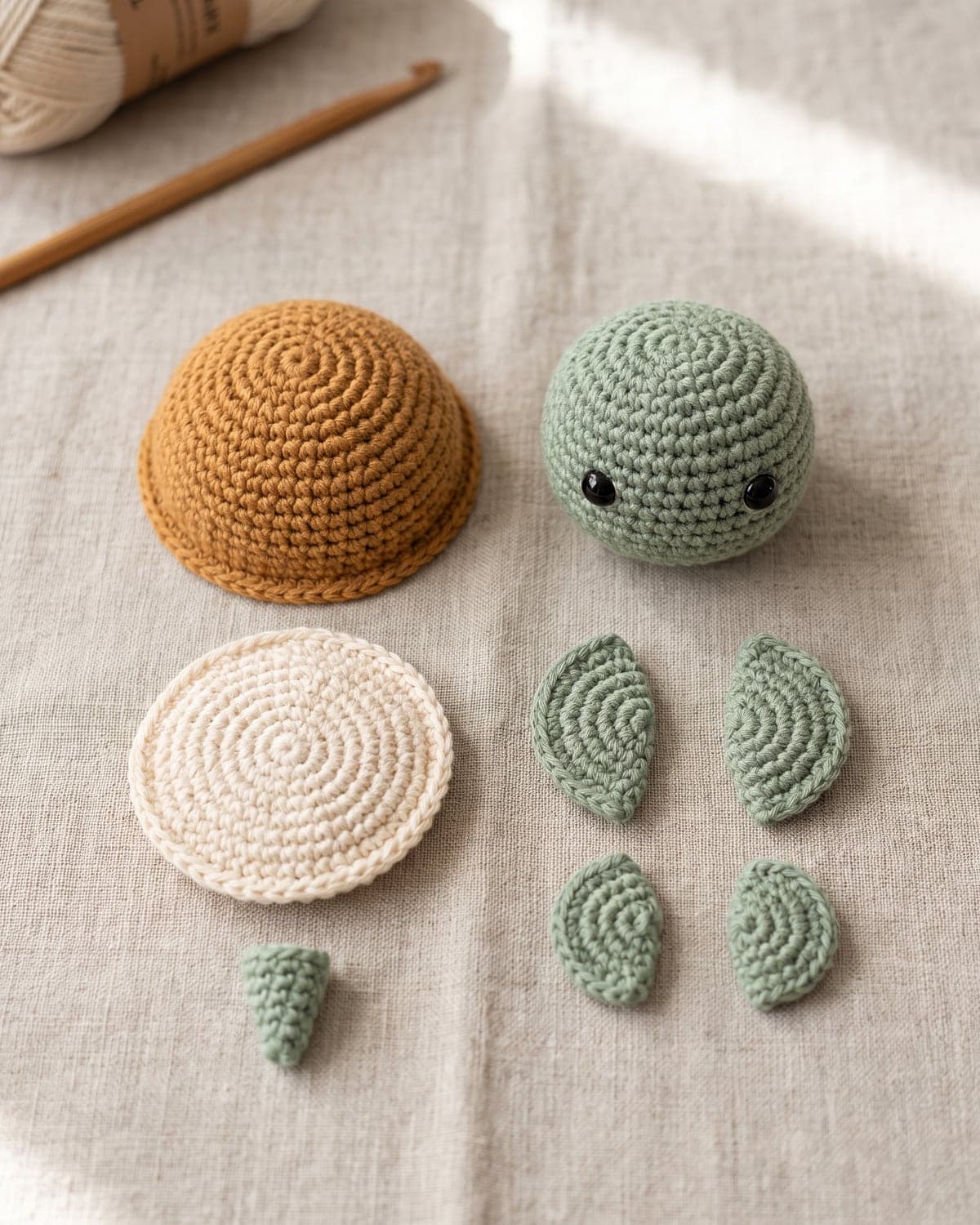 Crochet turtle pieces laid out on linen: caramel shell, cream belly circle, green head, four flippers and a tail